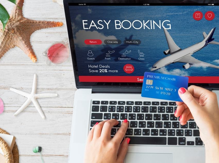 Online easy booking screen on laptop with airplane, credit card payment, and beach travel items.