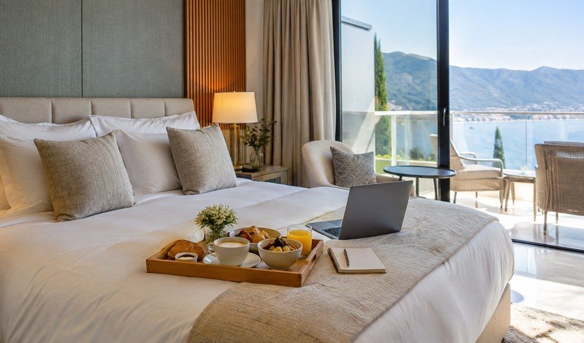 Bright hotel room with breakfast and laptop used to compare hotel offer value